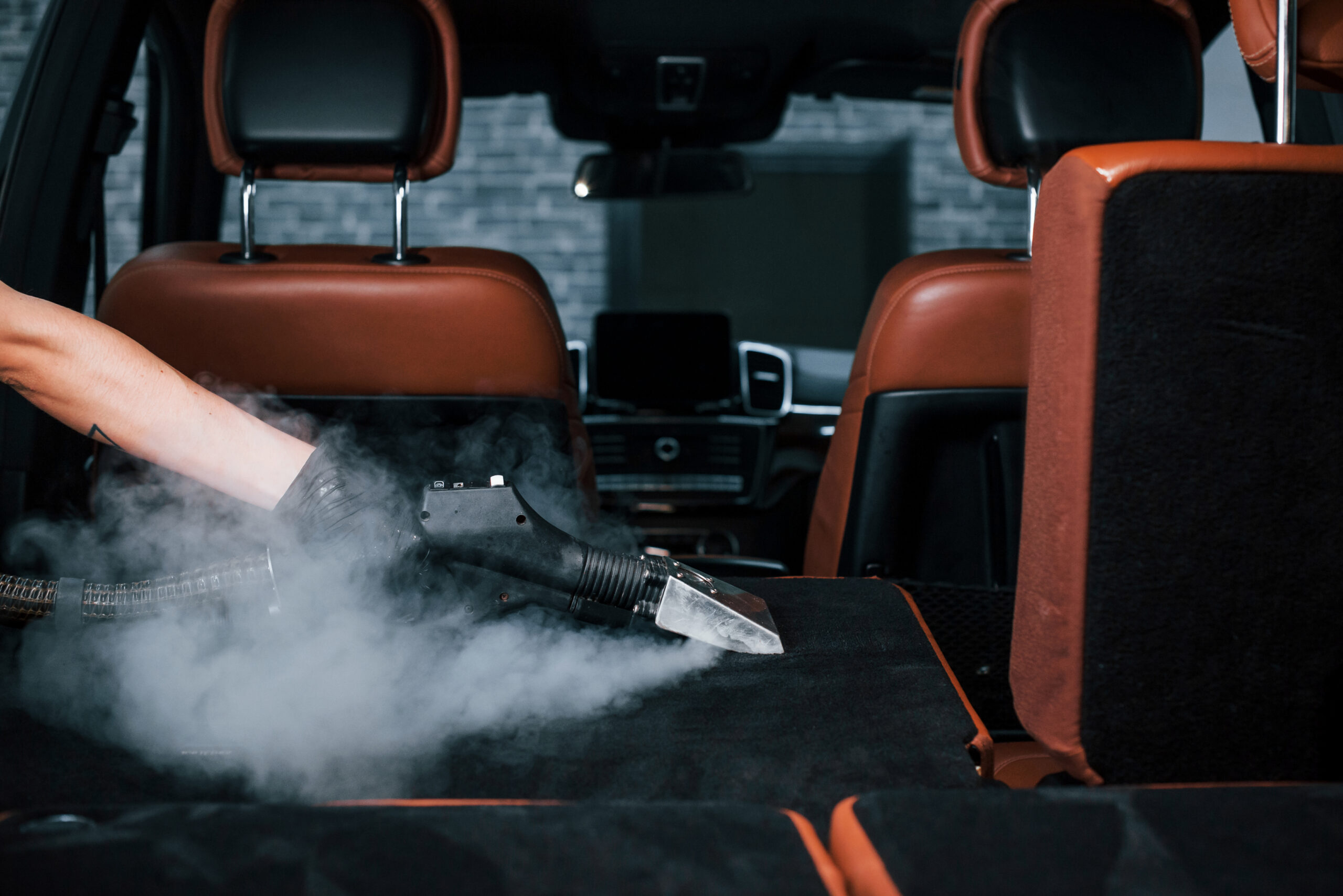 uses steam cleaner modern black automobile is service by woman inside car wash station scaled